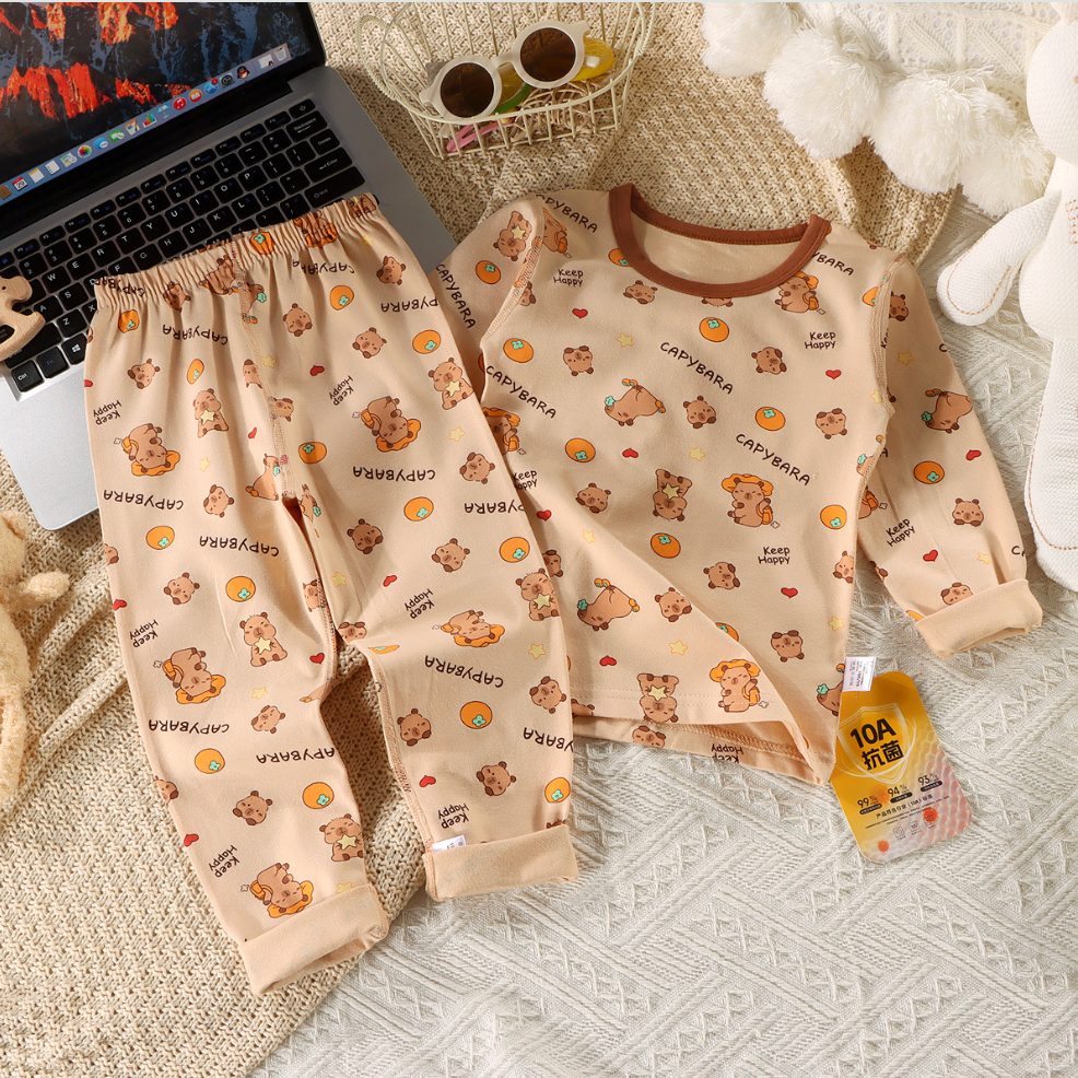 Children's pajama set with teddy bear pattern on a textured surface next to a laptop.