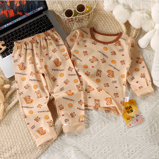 Children's pajama set with teddy bear pattern on a textured surface next to a laptop.