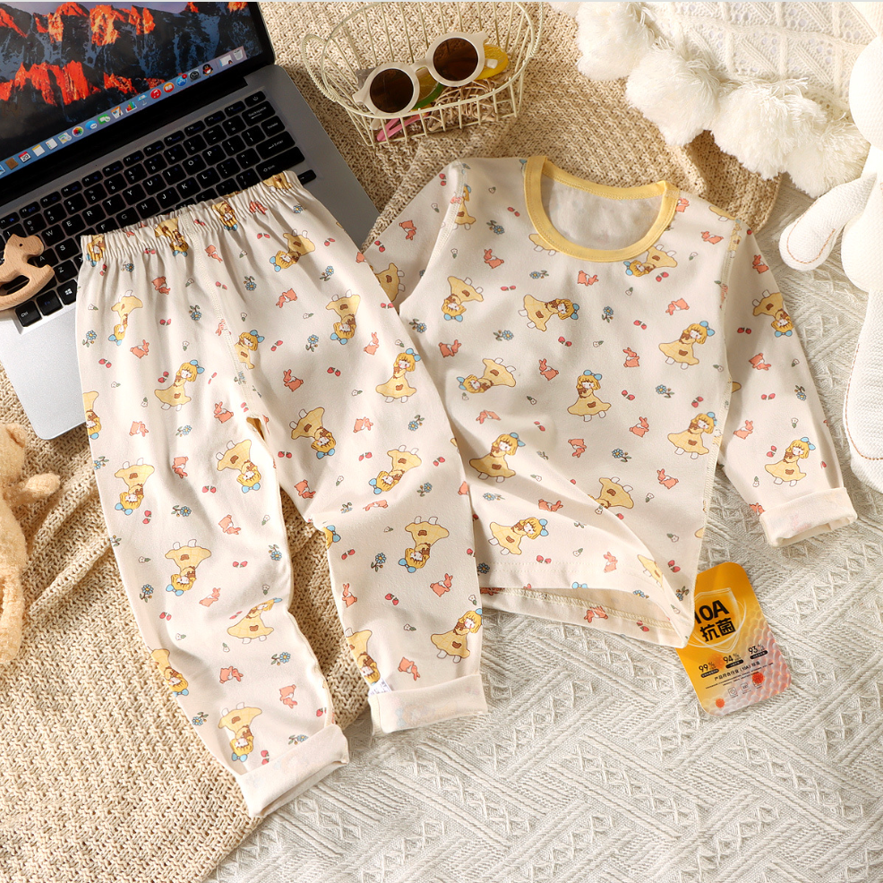 Children's pajama set with teddy bear pattern on a textured surface next to a laptop.