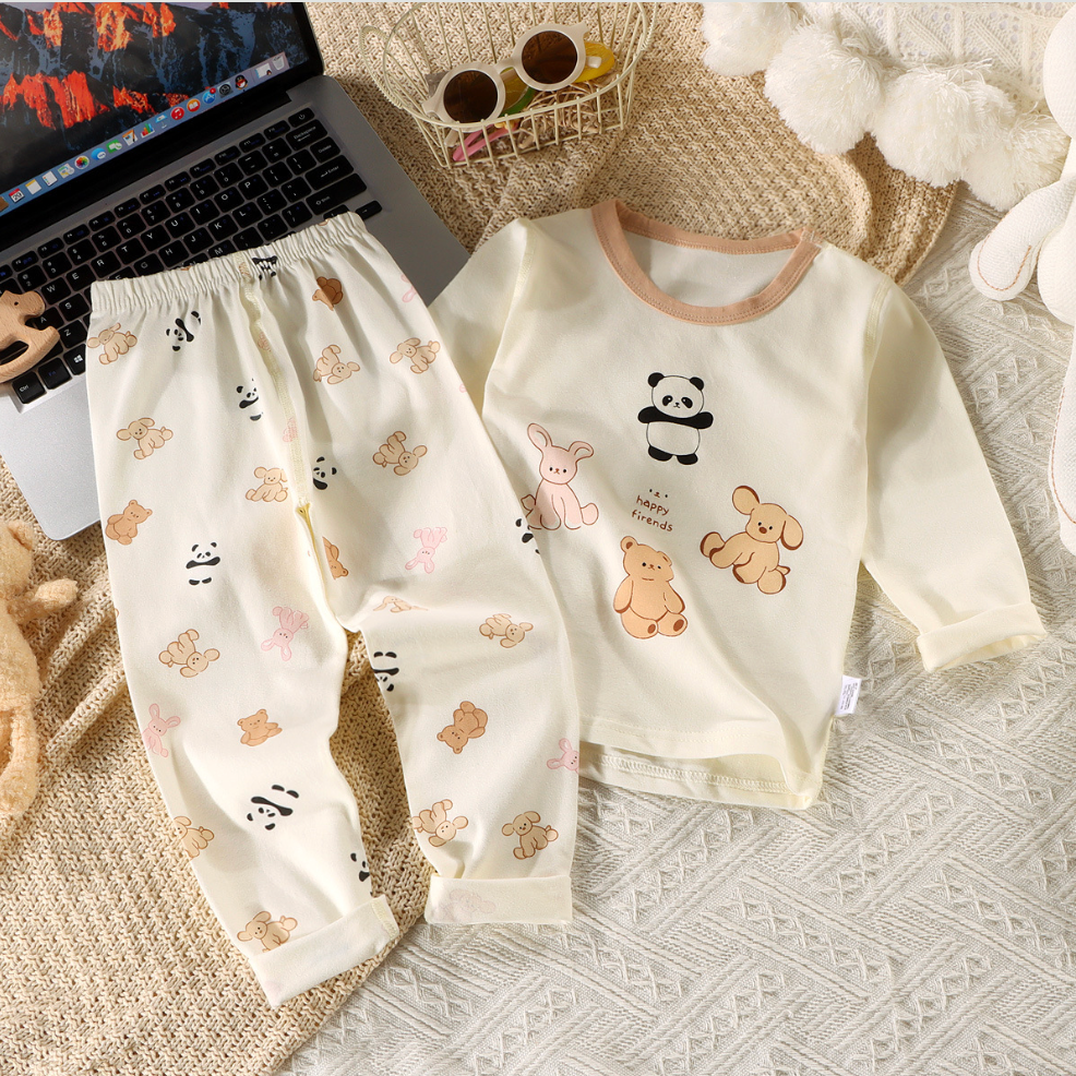 Children's pajama set with animal patterns on a textured surface next to a laptop.
