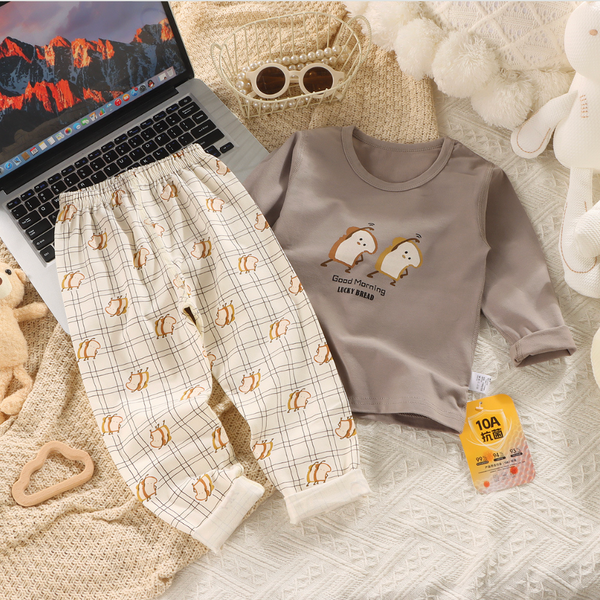 Children's pajama set with matching shirt and pants on a textured surface with a laptop.