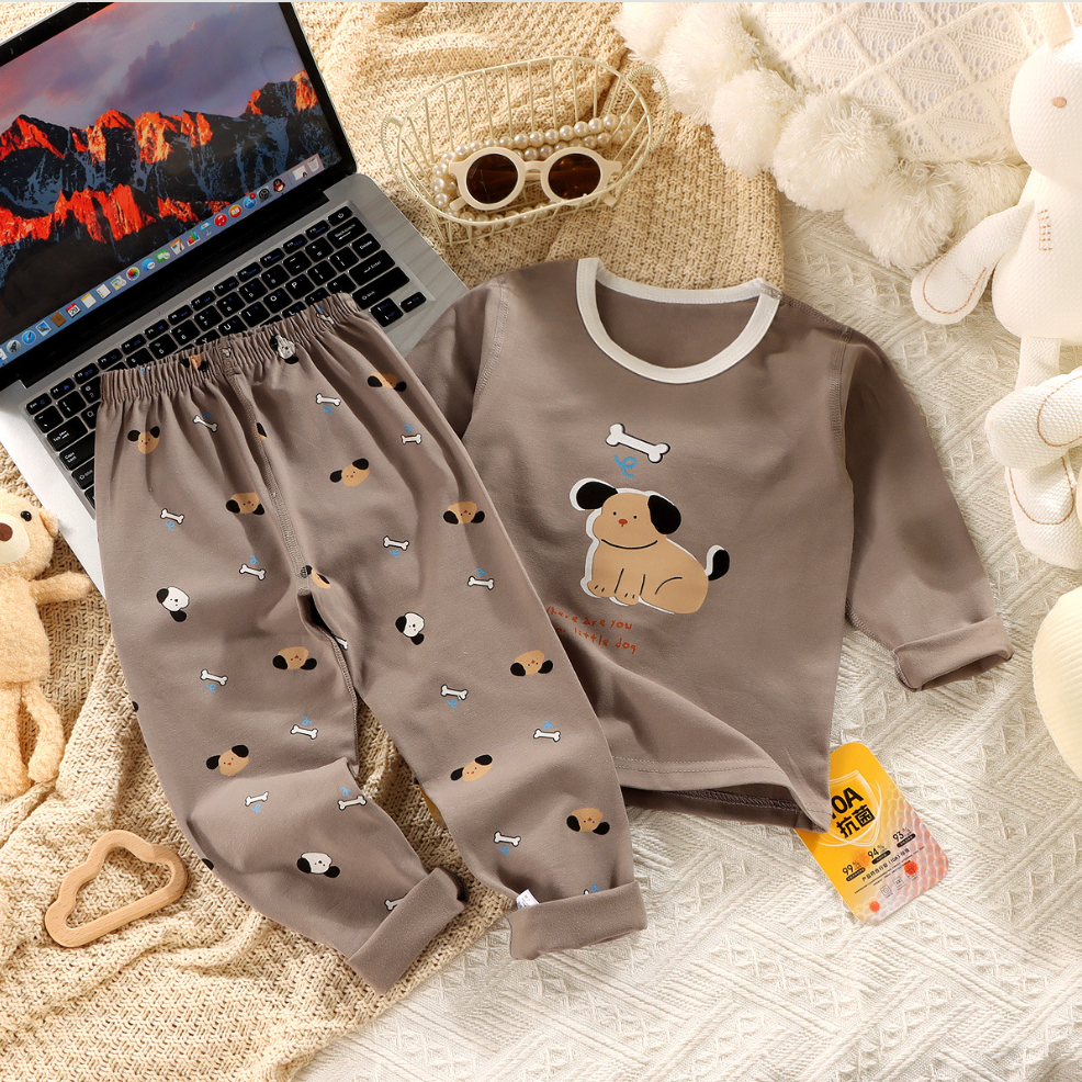Children's pajama set with dog design on a textured surface next to a laptop.