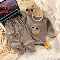 Children's pajama set with dog design on a textured surface next to a laptop.