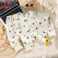 Children's pajama set with penguin pattern on a textured surface next to a laptop.