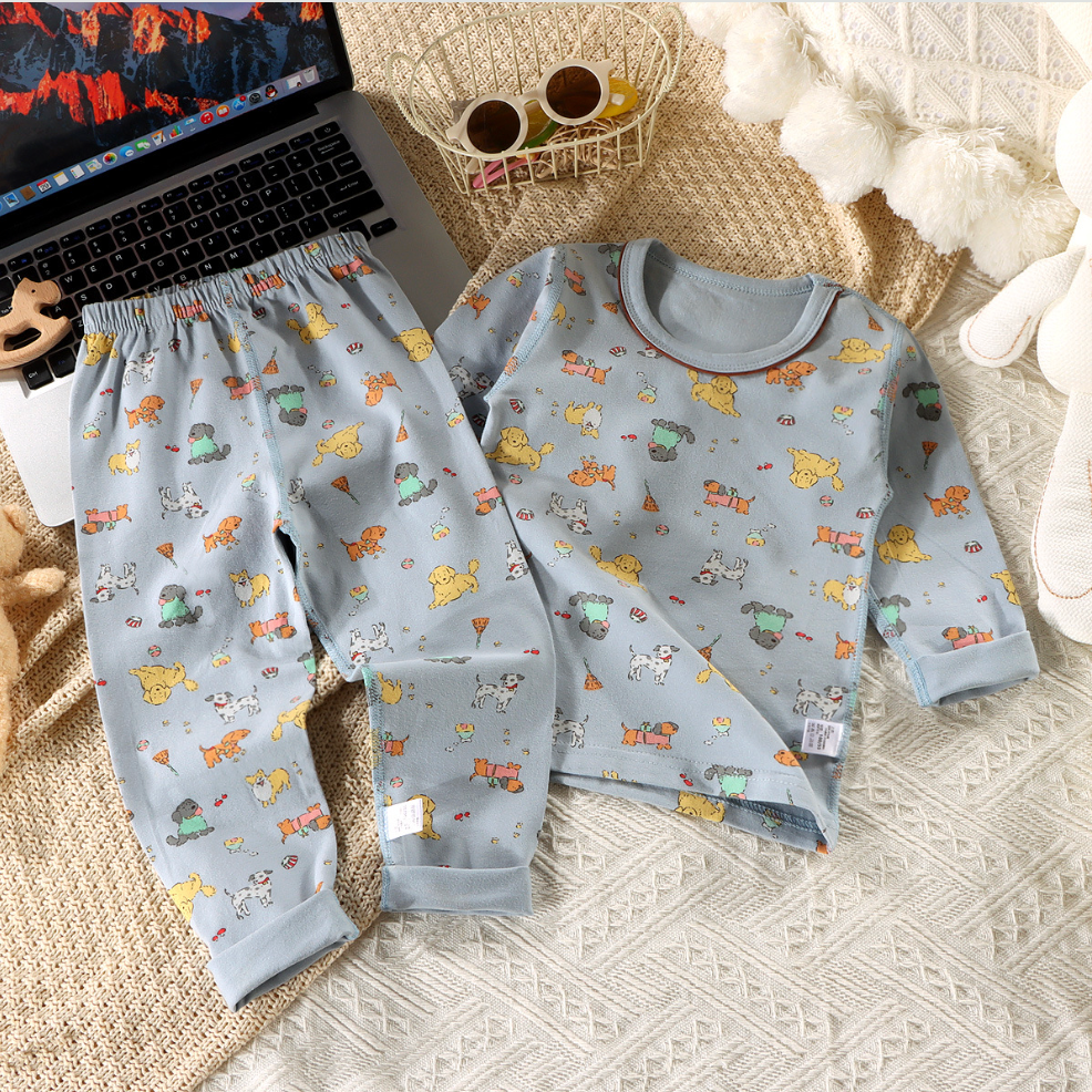 Children's pajama set with animal pattern on a textured surface next to a laptop.