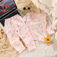 Children's pink pajama set with cartoon patterns on a textured surface next to a laptop.